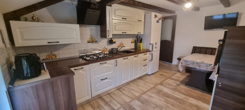 Bucătăria complet echipată, cu mobilier alb, aragaz, cuptor cu microunde și zonă de luat masa