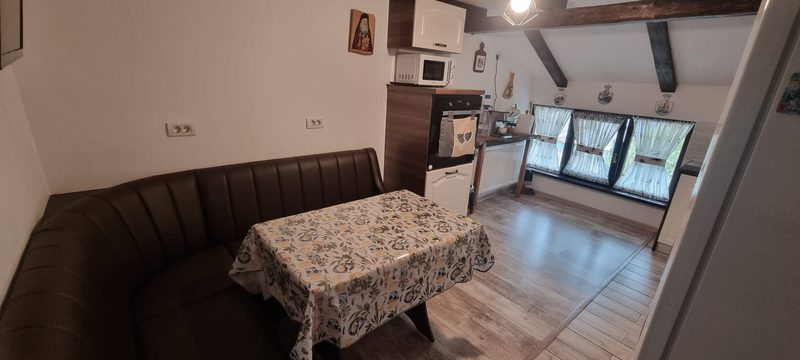 Masa din bucătărie cu față de masă cu model, banchetă de piele și ferestre luminoase