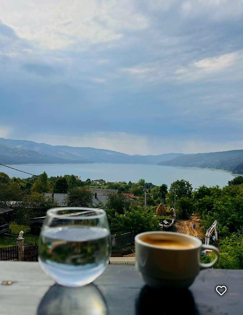 Cană de cafea și pahar de apă pe balustrada terasei, dimineața, cu Lacul Bicaz în fundal