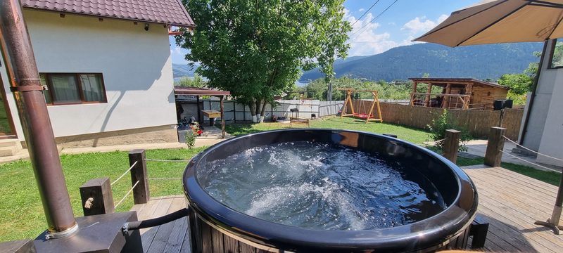 Ciubărul cu apă în mișcare, așezat pe deck, cu casa și curtea în fundal