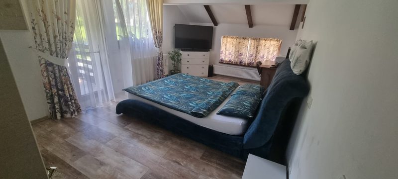 Dormitor luminos cu pat, perdele albe și pardoseală de lemn