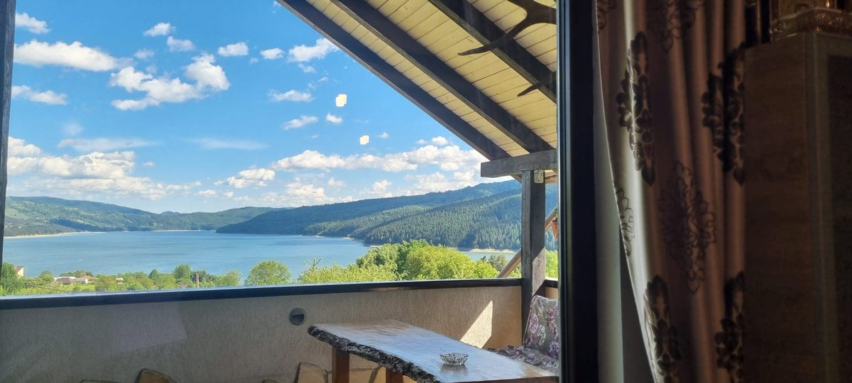 Priveliștea spre Lacul Bicaz văzută din foișorul Casei David, cu cer senin și munți la orizont
