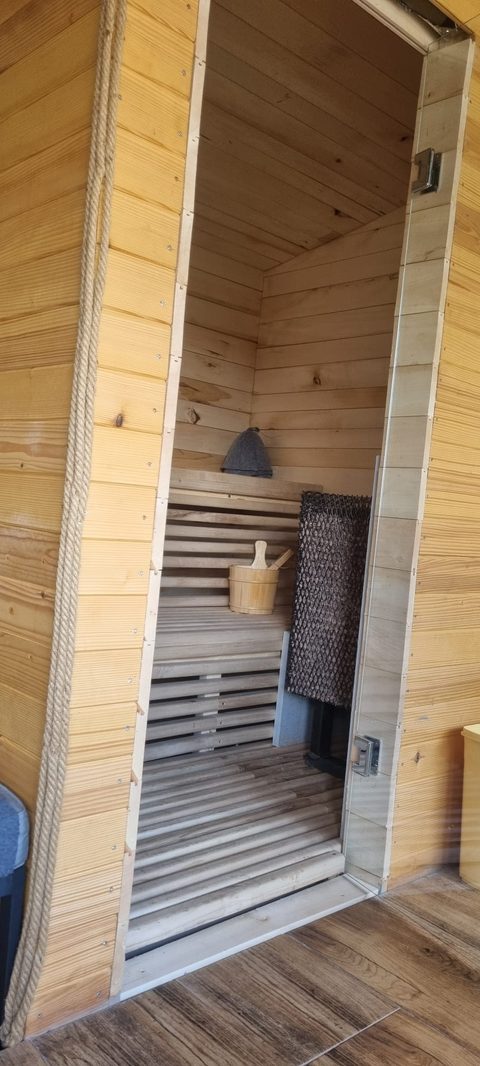 Intrarea în sauna de lemn de la Casa David, cu bănci și pereți din lemn deschis la culoare