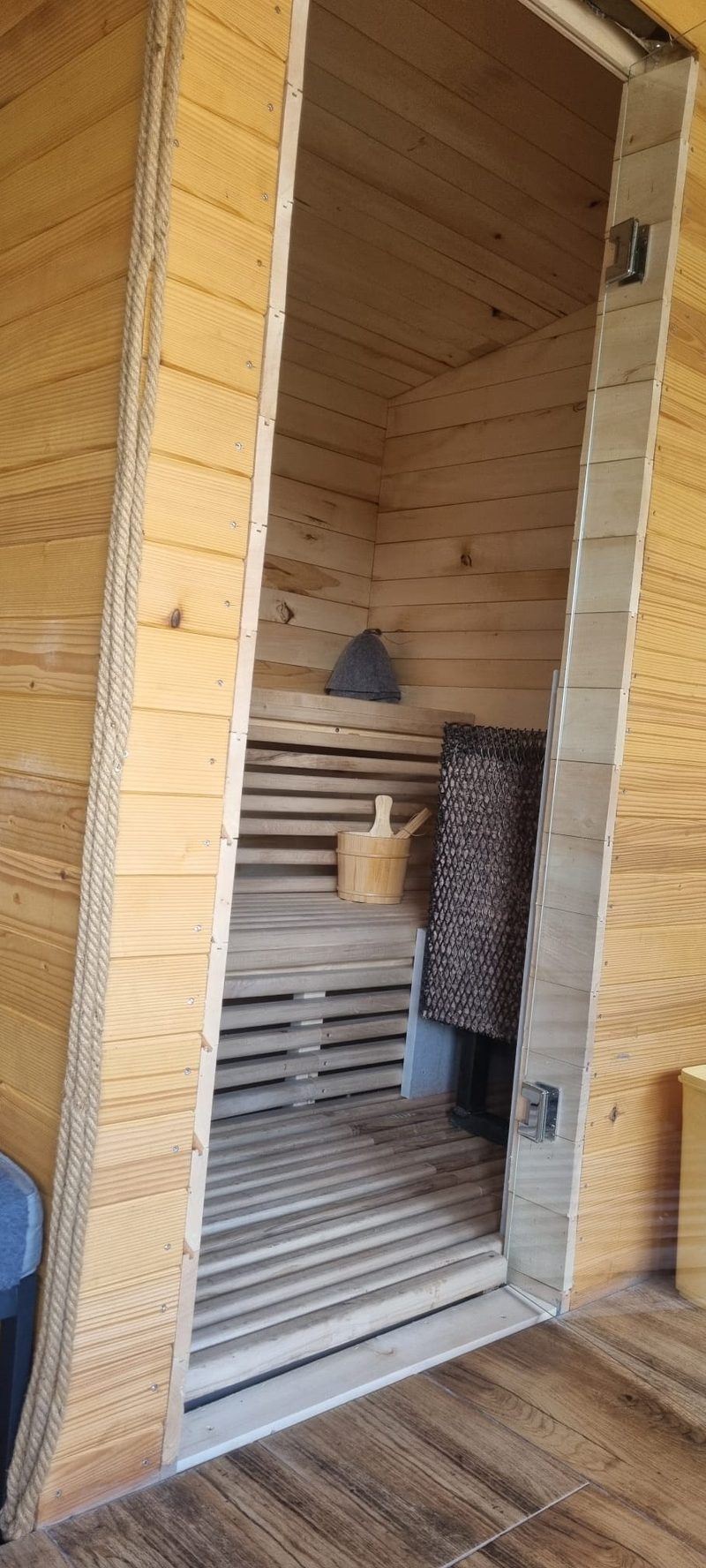 Intrarea în sauna de lemn de la Casa David, cu bănci și pereți din lemn deschis la culoare